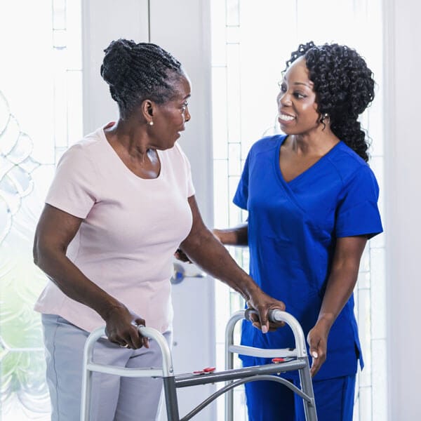 Caregiver helping senior woman with walker