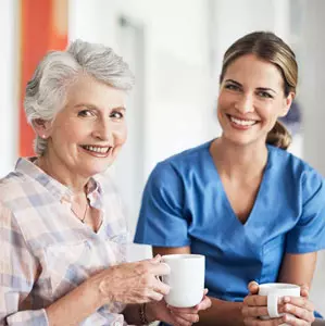 Caregiver and senior woman drinking coffee