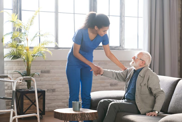 caregiver assisting senior man stand up after stroke