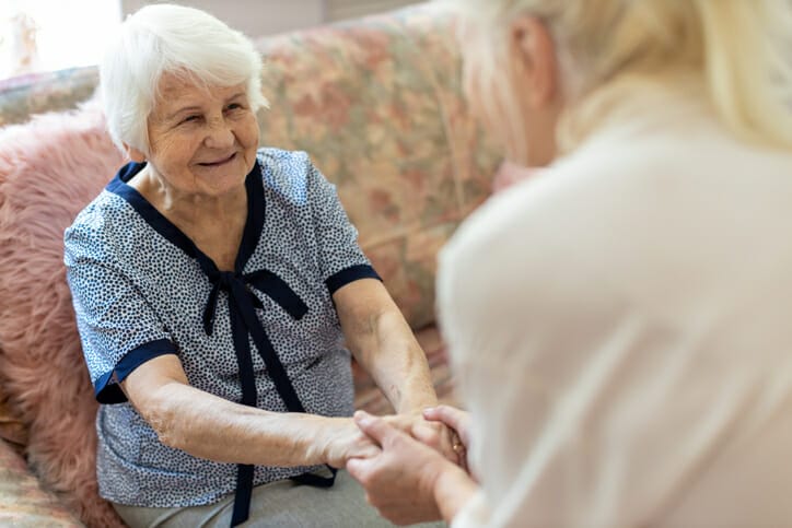 caregiver helping senior lady up off couch