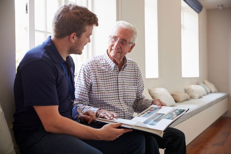 A professional in-home caregiver uses reminiscence therapy to engage with an older man who has dementia.
