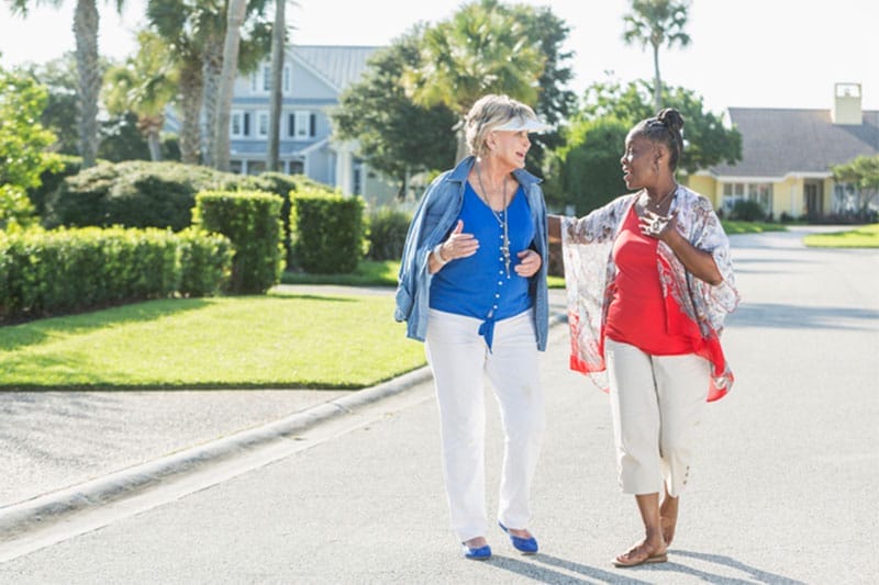 Two women take steps to improve heart health by going for a walk outdoors.