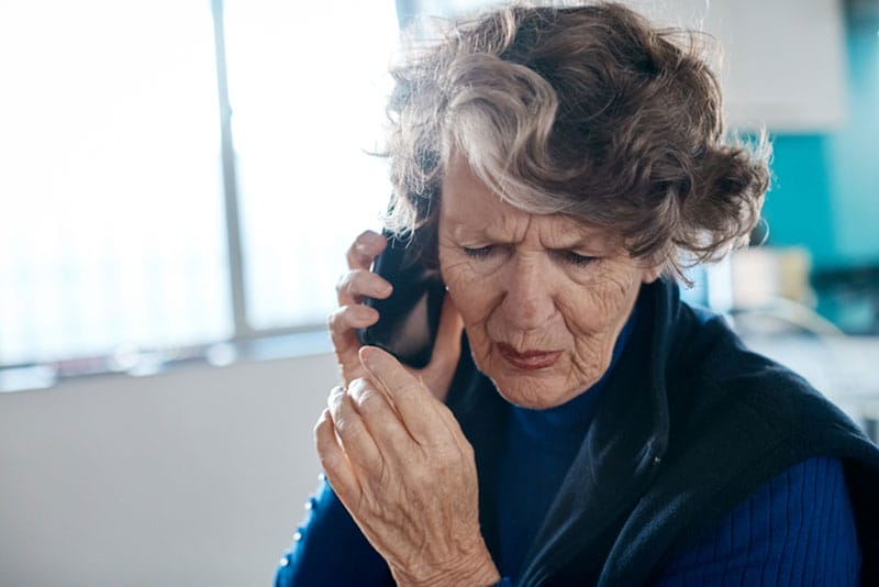 A woman frowns as she listens to one of the latest AI voice cloning scams on the phone.